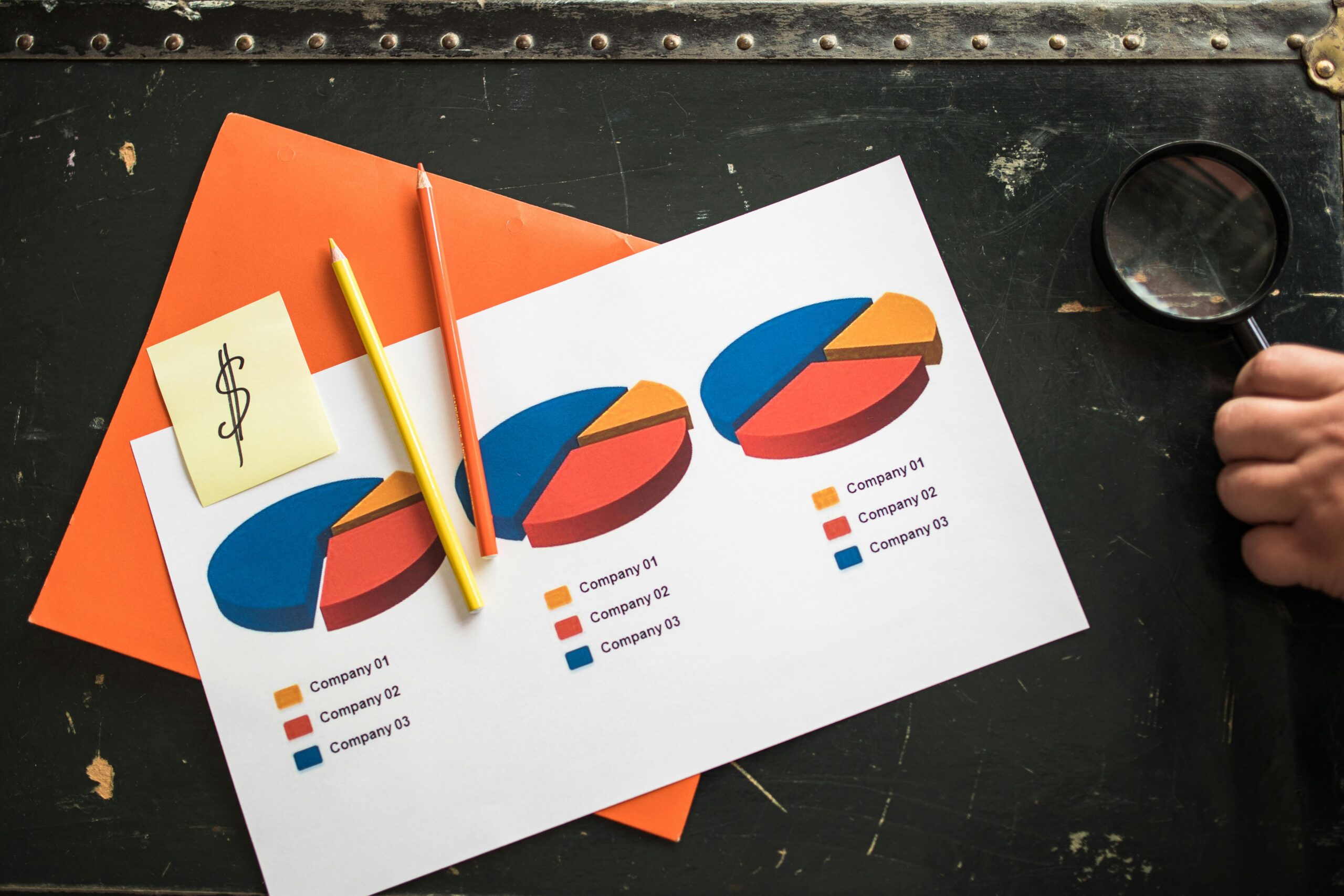 Colorful pie charts on paper with office supplies on a desk, illustrating financial data analysis.